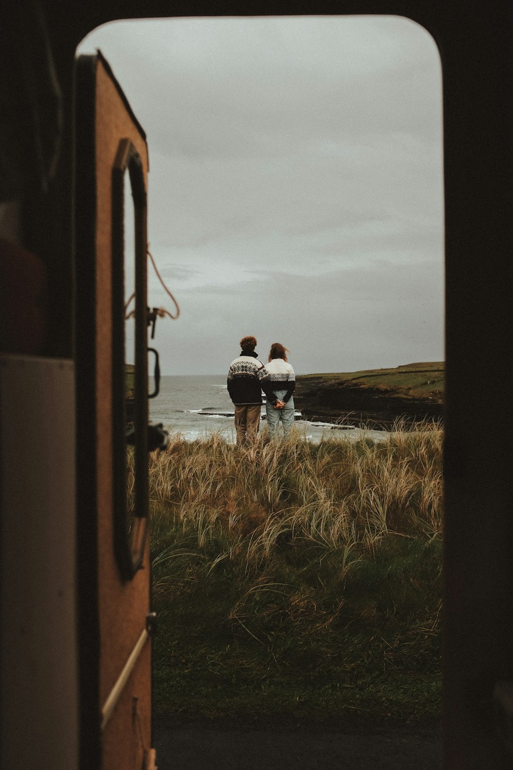 a couple of people standing on top of a grass covered field