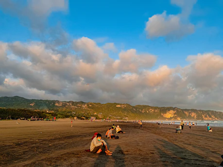 a group of people standing on top of a sandy beach