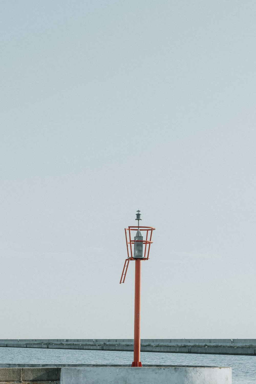 a tall red tower sitting next to a body of water