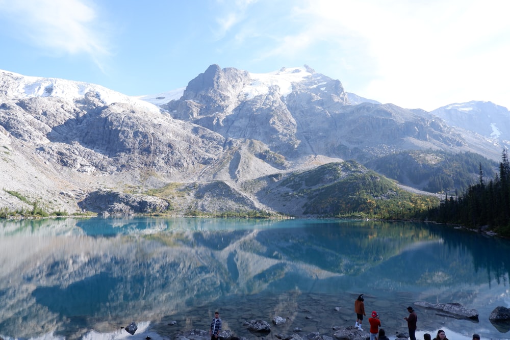 a group of people standing next to a mountain lake