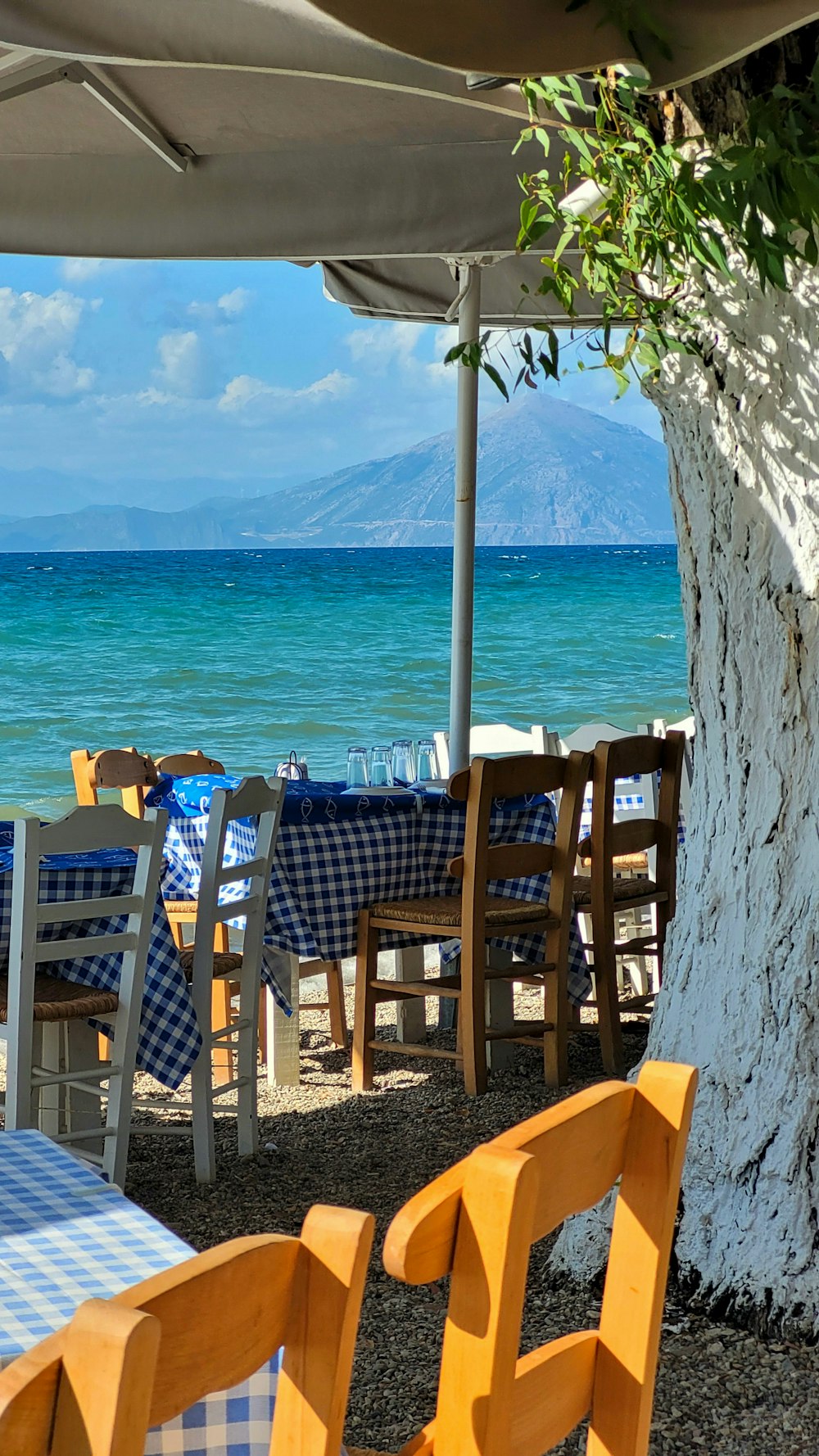 a table and chairs under an umbrella on the beach
