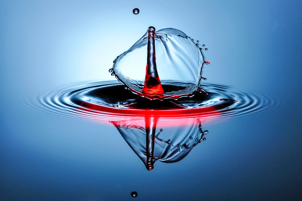 uma gota de água com uma luz vermelha refletindo nela