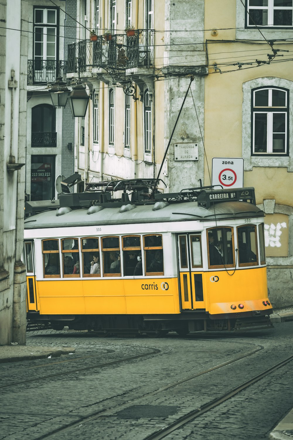 a yellow trolley car traveling down a street next to tall buildings