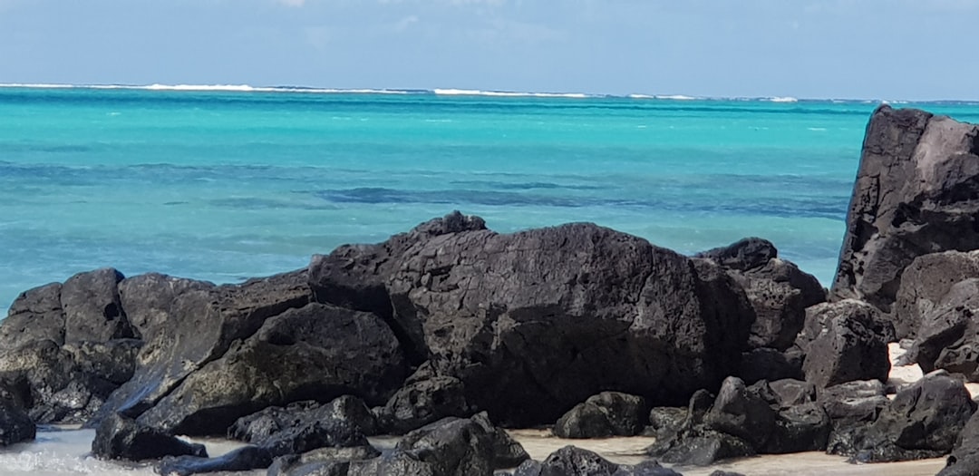 a couple of rocks sitting on top of a beach next to the ocean,