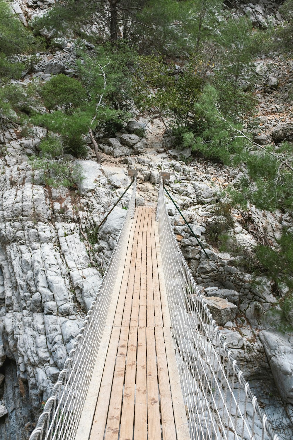 a wooden suspension bridge over a rocky river