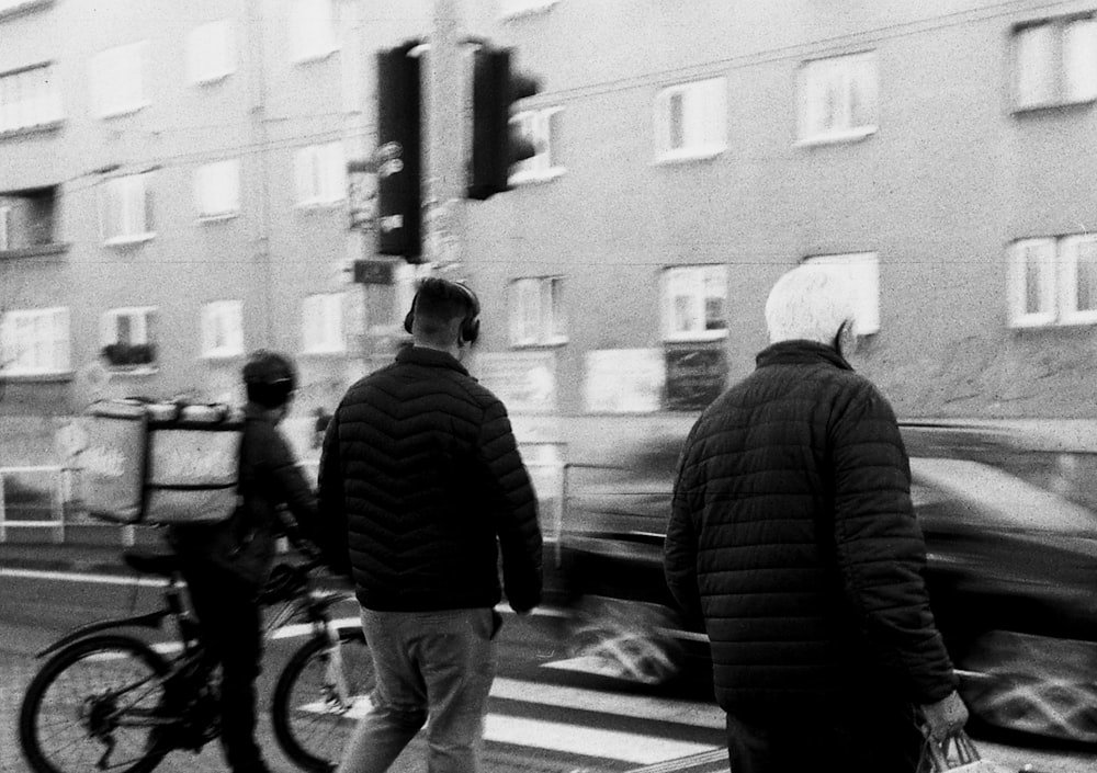 a black and white photo of two people crossing the street