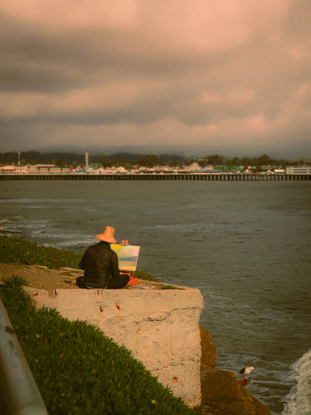 a man sitting on a rock next to a body of water