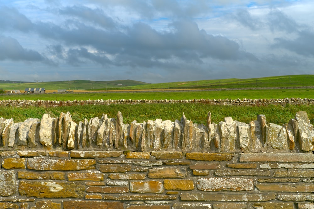 a stone wall with a field in the background
