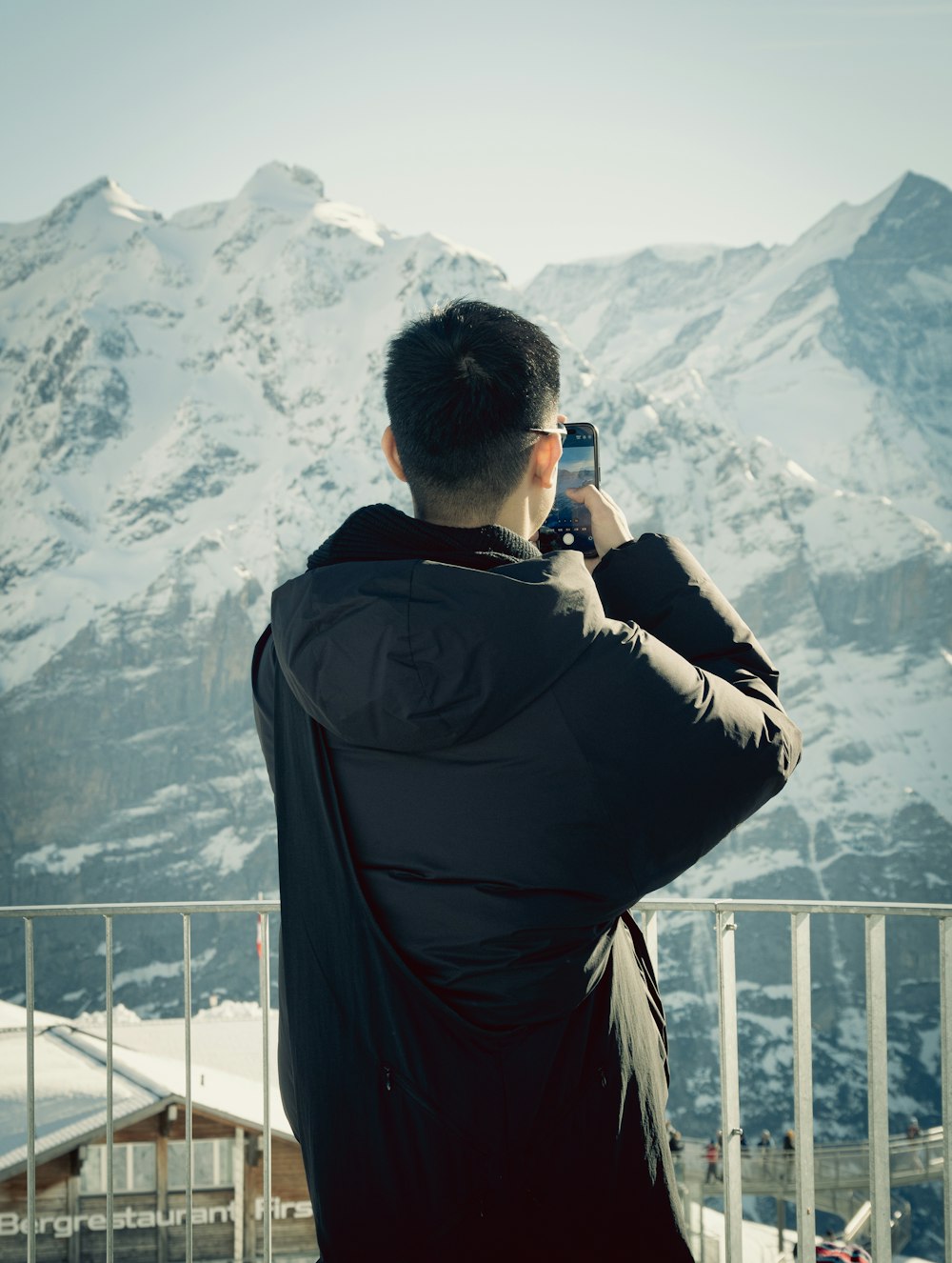 a man taking a picture of a snowy mountain