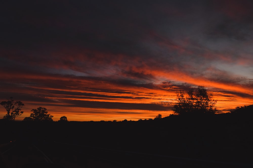 a sunset with clouds and trees in the background