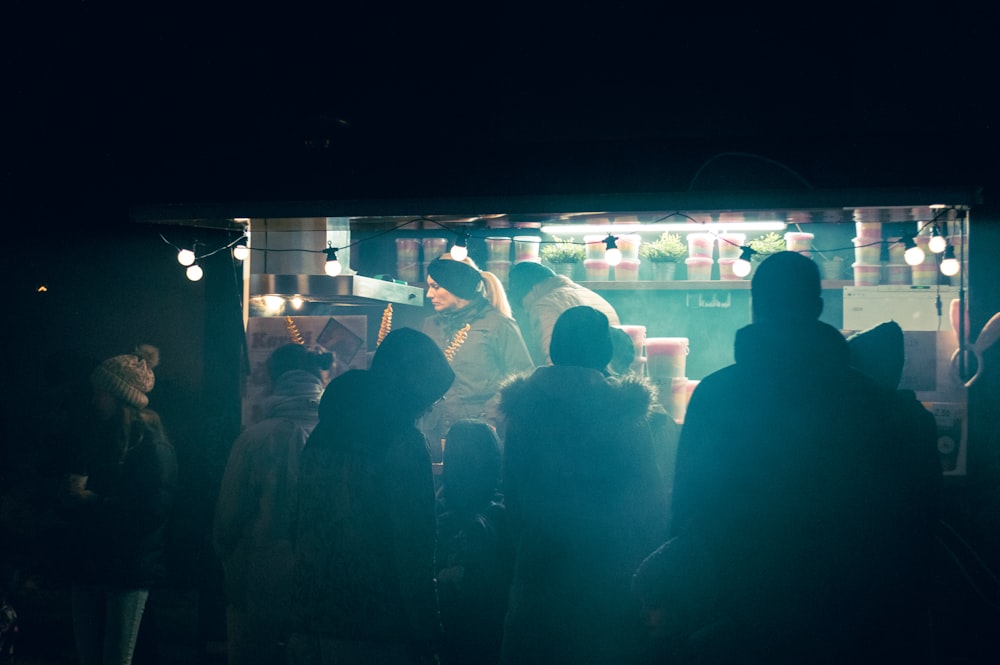 a group of people standing around a bar at night