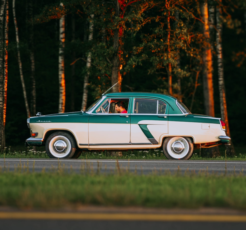 a green and white car parked on the side of the road