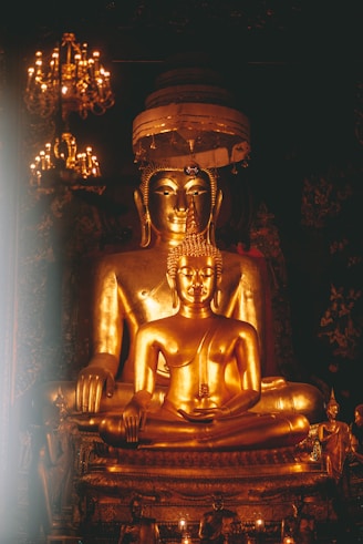 a golden buddha statue sitting in front of a chandelier