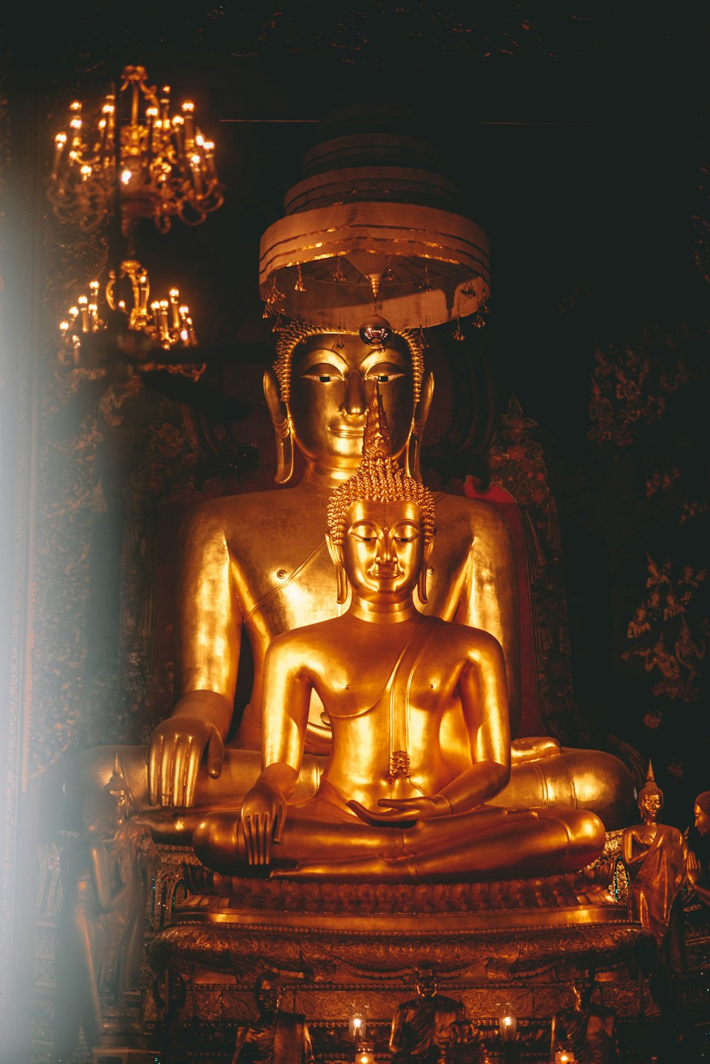a golden buddha statue sitting in front of a chandelier