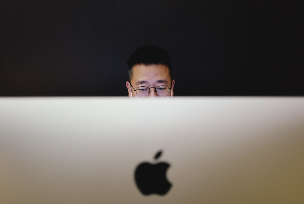 a man looking at a laptop screen with an apple logo on it