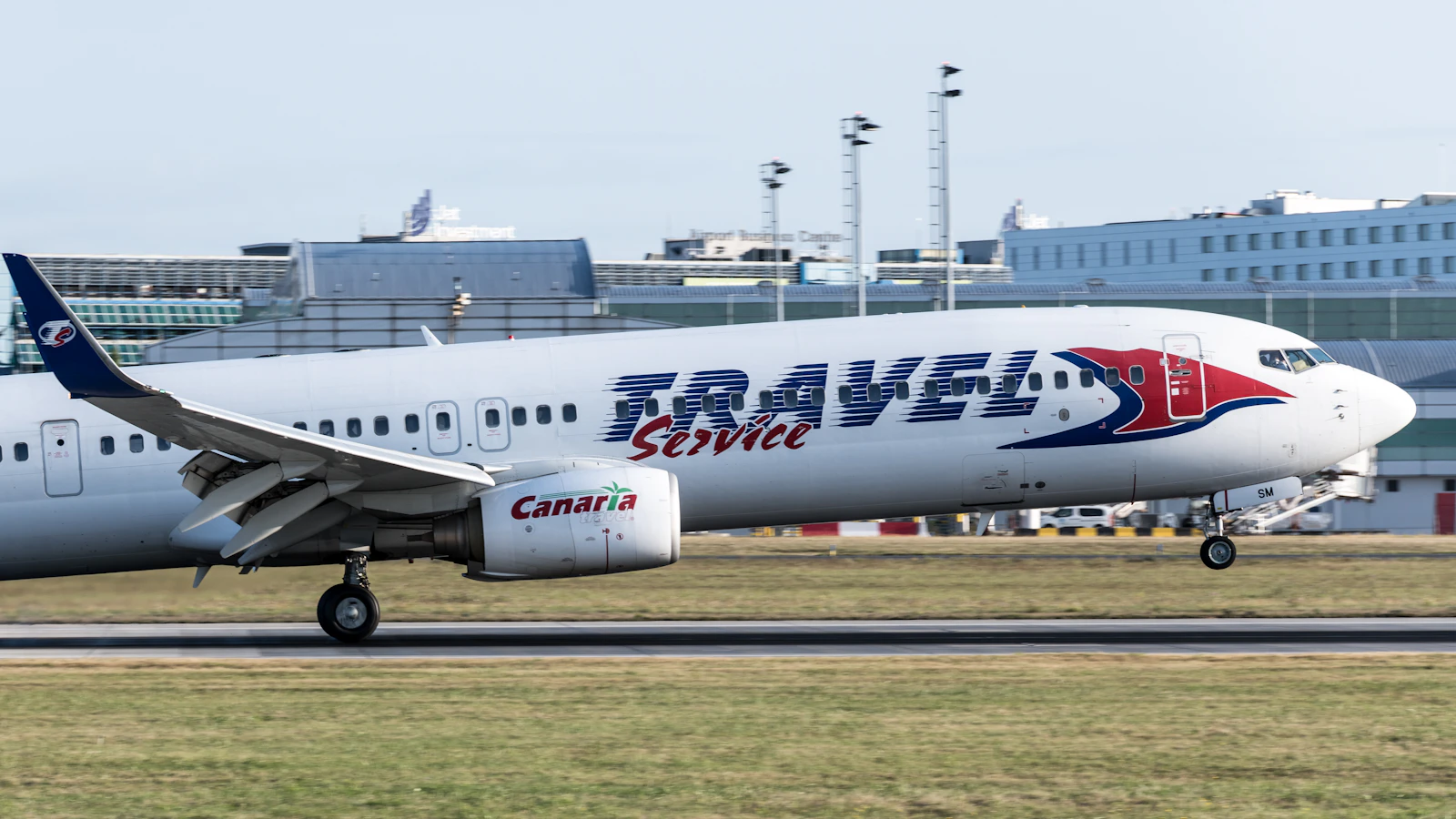 A large passenger jet climbing into a clear sky shortly after takeoff from an airport runway