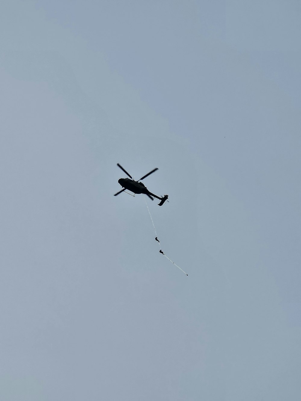 a helicopter flying in the sky with a parachute
