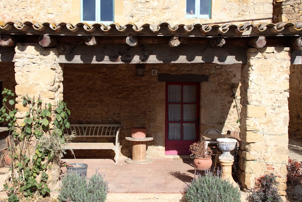 a patio with a bench and potted plants