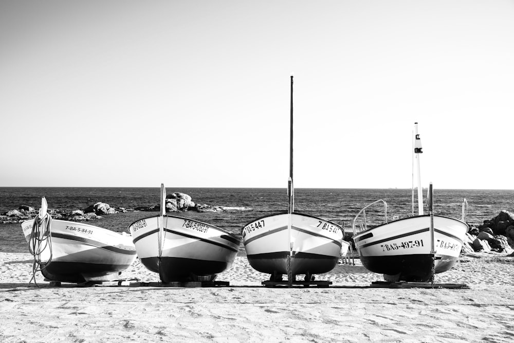 a group of three boats sitting on top of a sandy beach