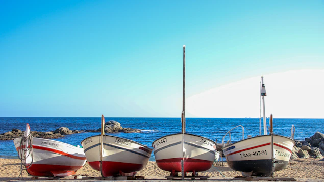 three boats sitting on a beach next to the ocean