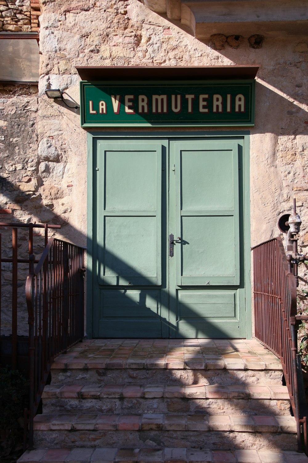 緑色のドアとLa Vermuteriaと書かれた看板のある建物