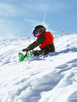 a young child sitting in the snow on a snowboard