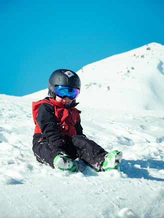 a young child sitting in the snow on a snowboard