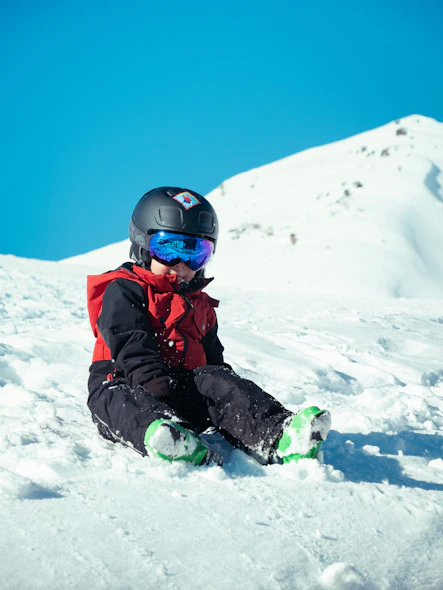 a young child sitting in the snow on a snowboard