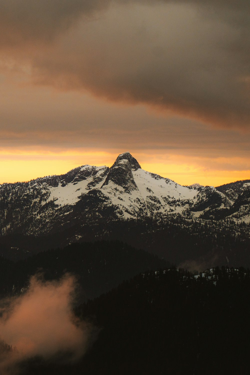 a mountain covered in snow under a cloudy sky