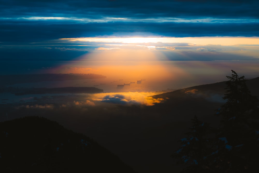 the sun is shining through the clouds over the mountains