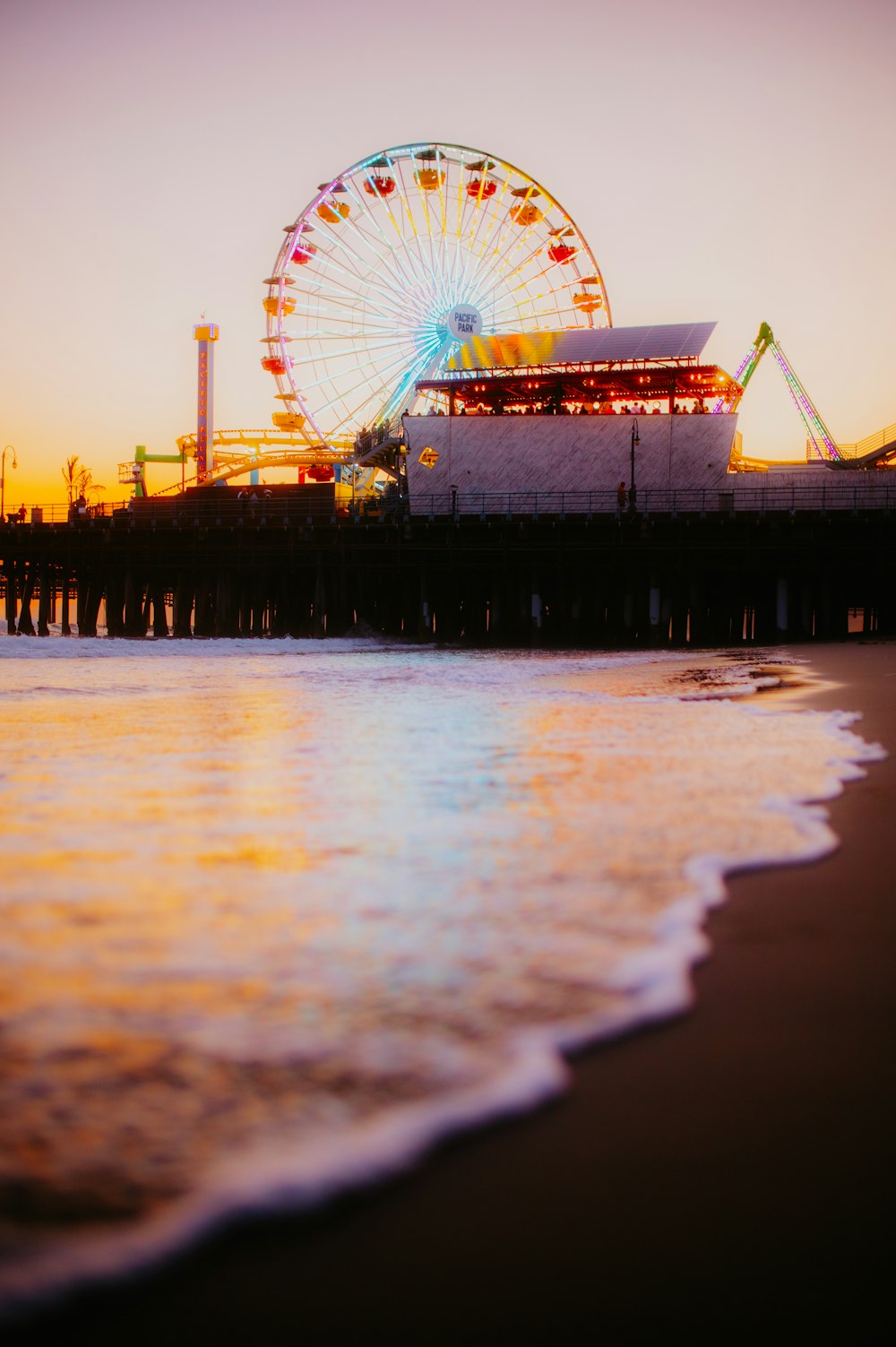 a ferris wheel sitting on top of a pier next to the ocean