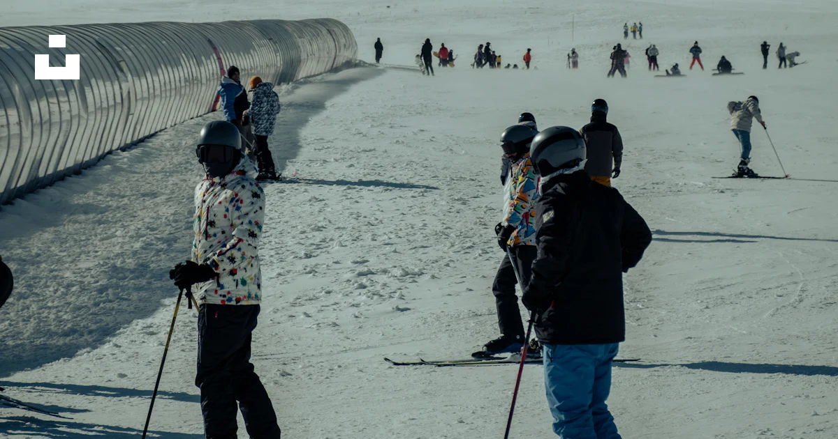 A group of people riding skis on top of a snow covered slope photo ...