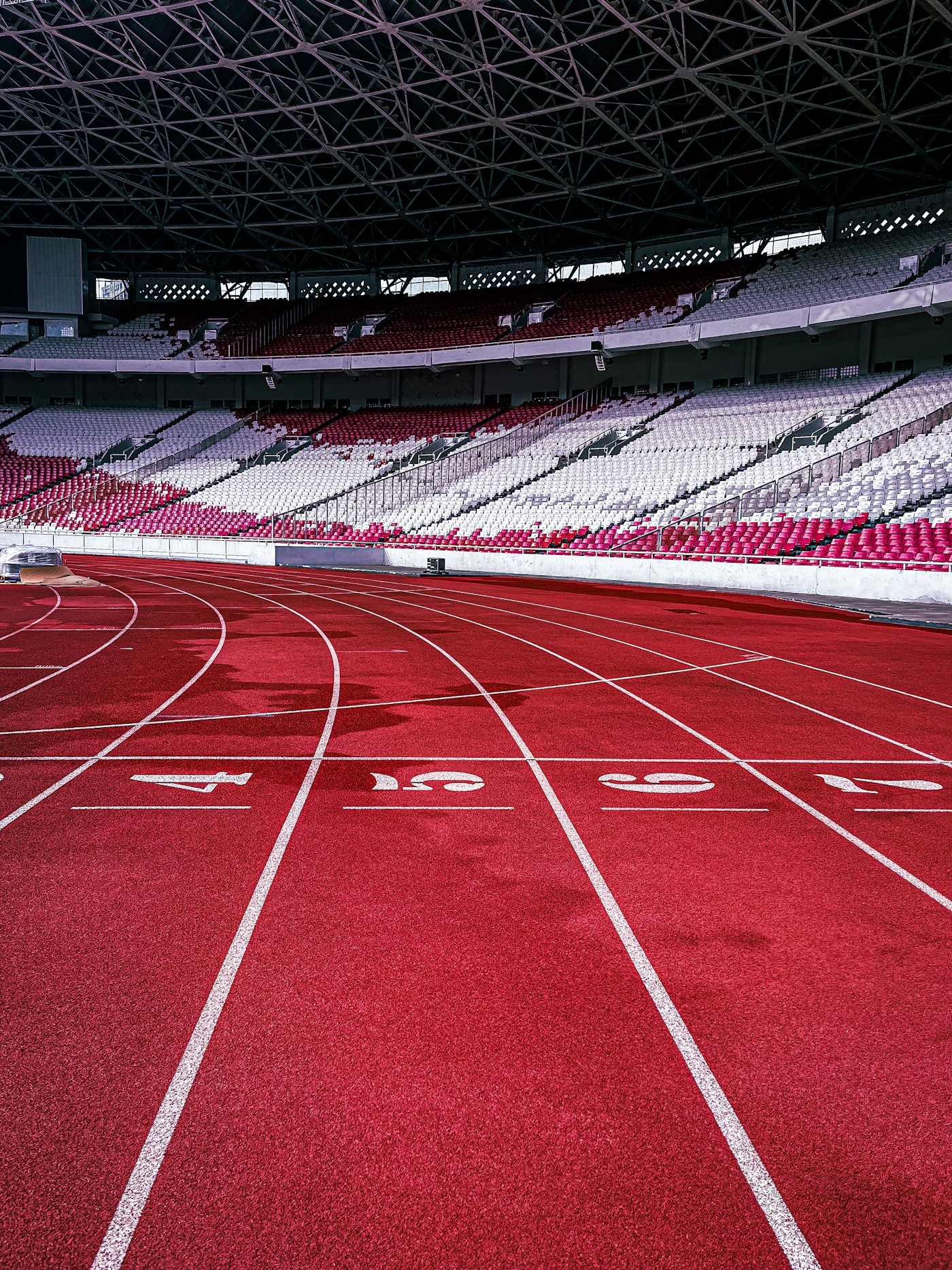 An empty red running track curving through a stadium