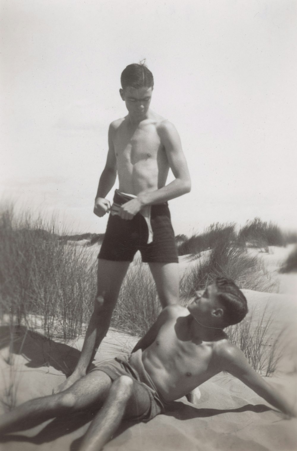 a man laying on the beach next to another man