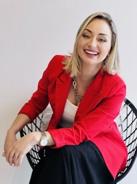 a woman in a red jacket sitting on a chair