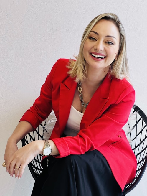a woman in a red jacket sitting on a chair