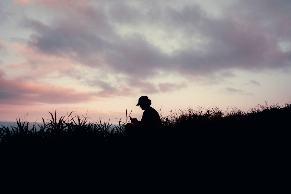 a silhouette of a person sitting on a hill