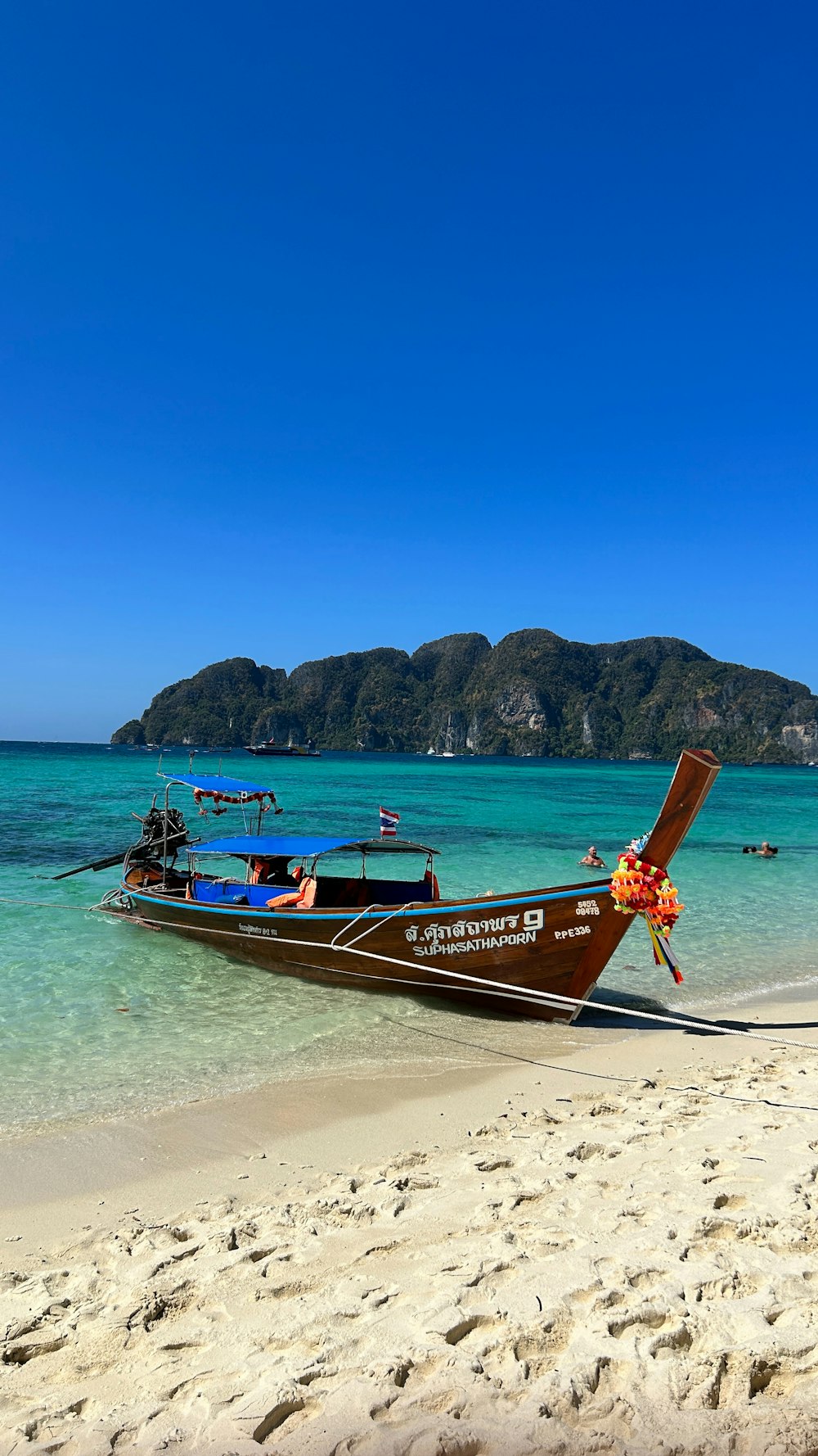 a long boat on the beach with people in the water