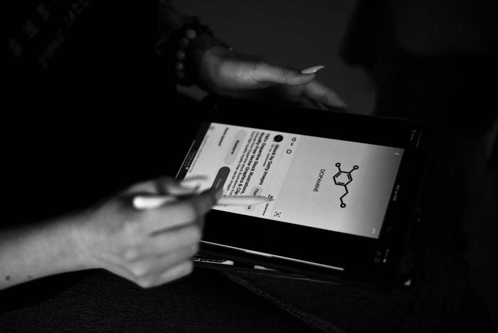 a person holding a pen and writing on an electronic device