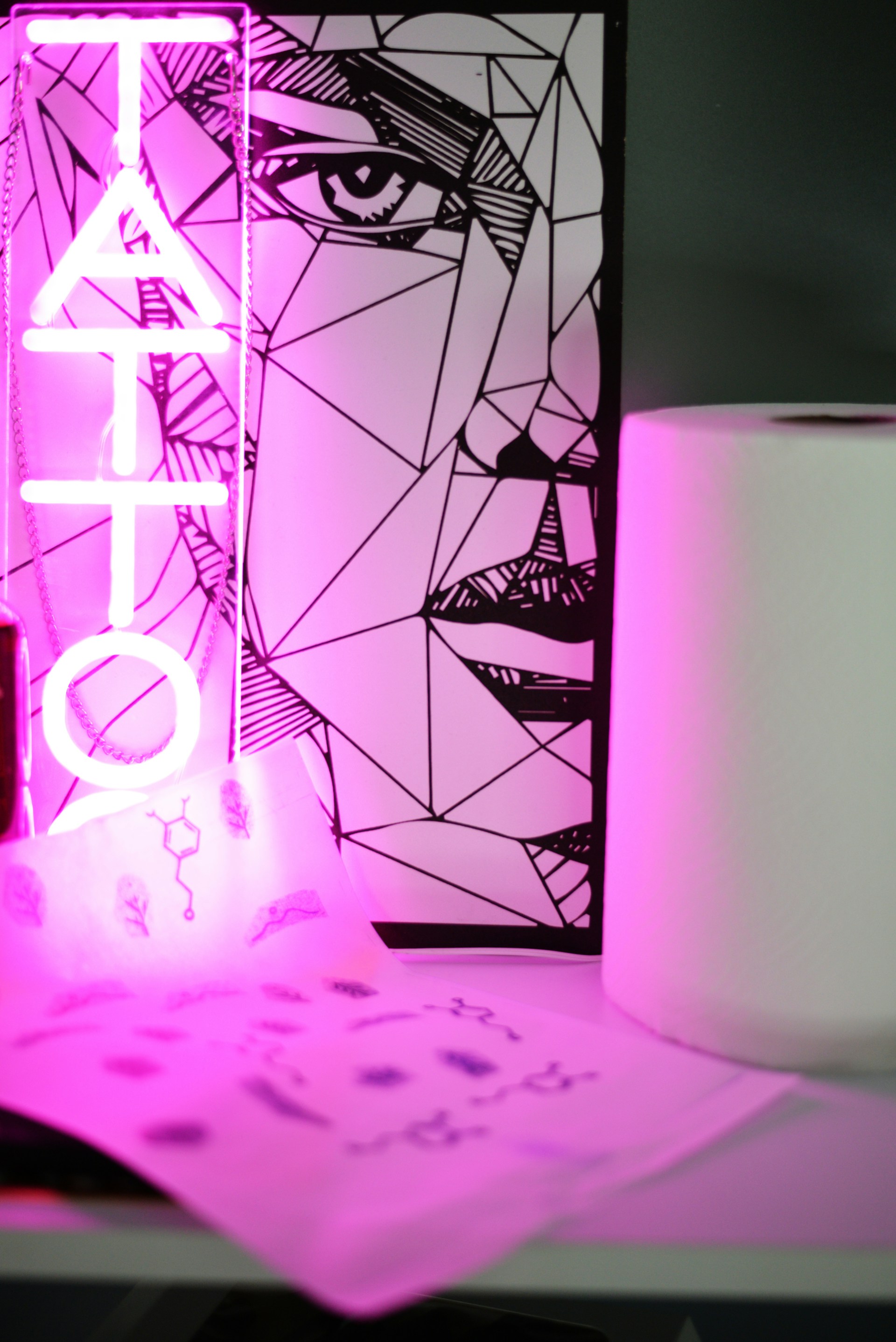 a pink neon sign sitting next to a roll of toilet paper