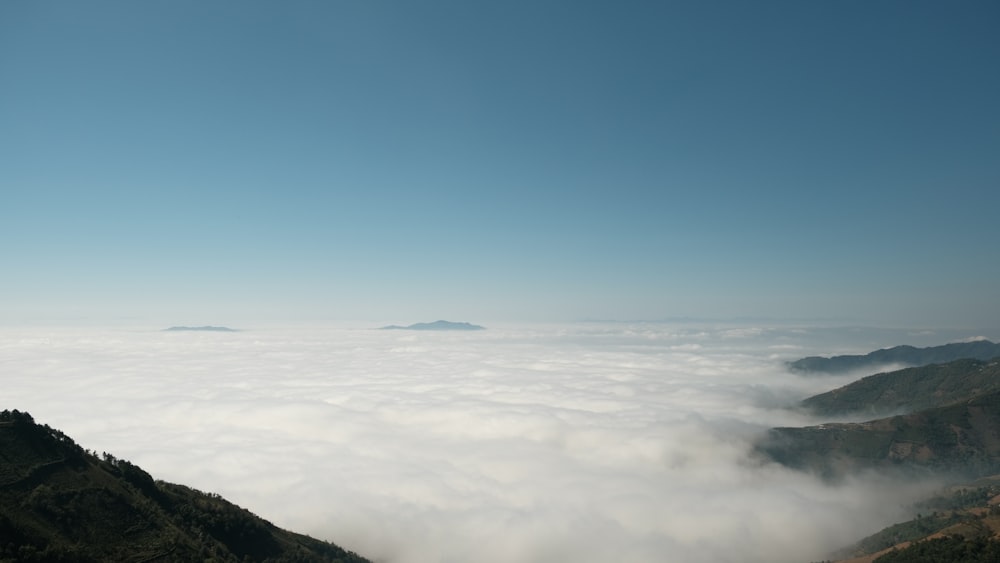 a view of the mountains and clouds from the top of a hill