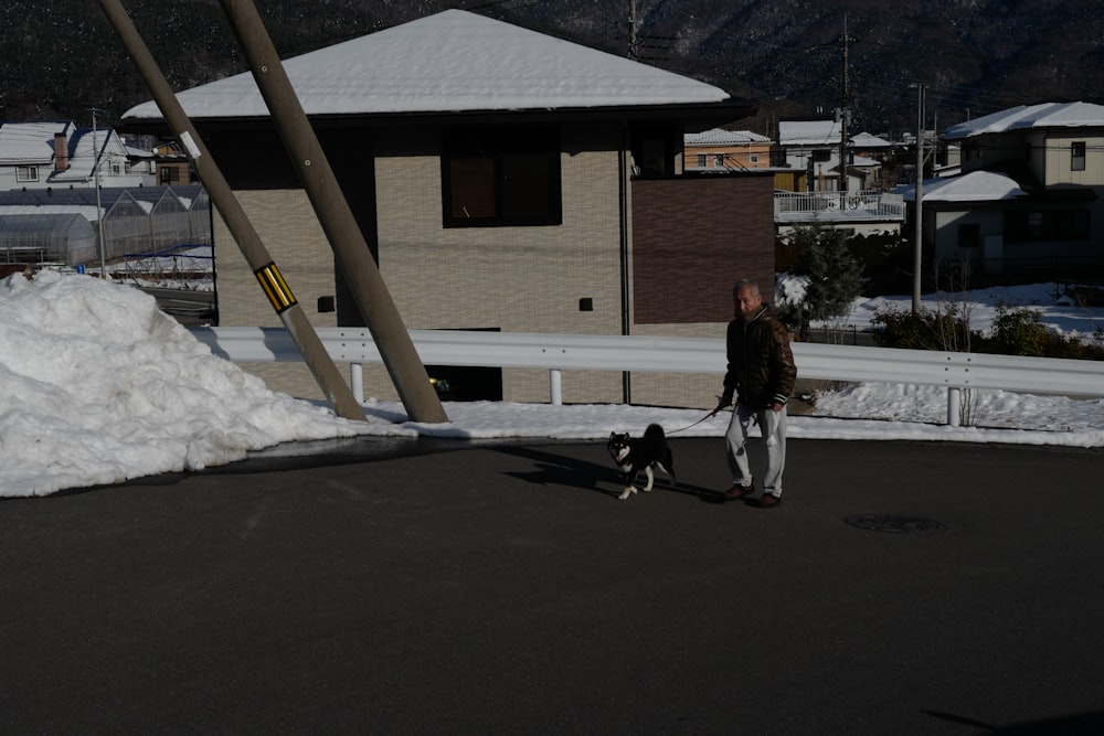 a man walking a dog on a leash in the snow