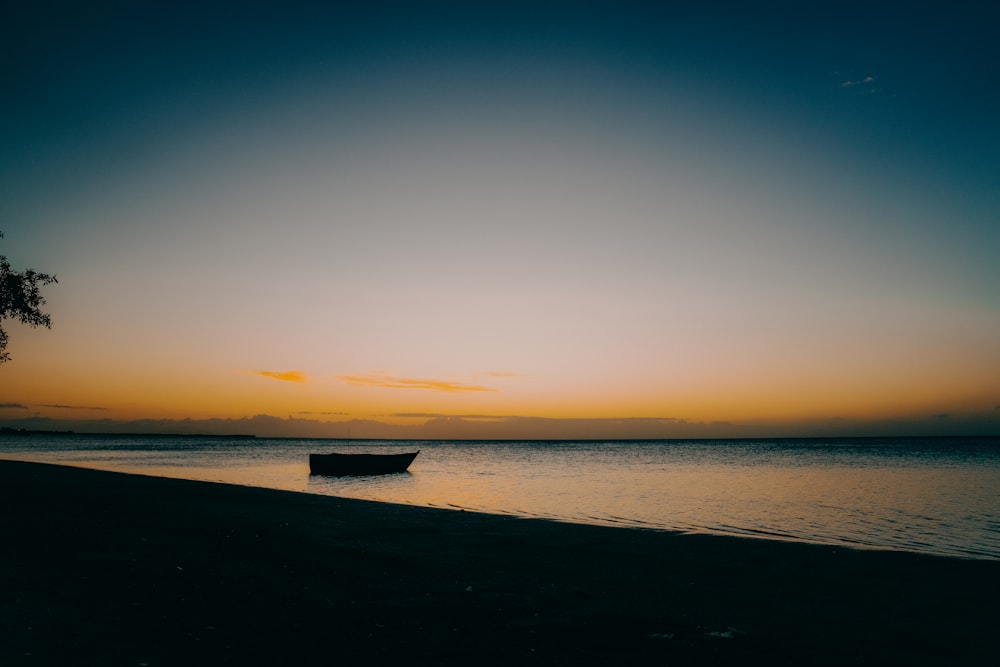 a boat is sitting in the water at sunset
