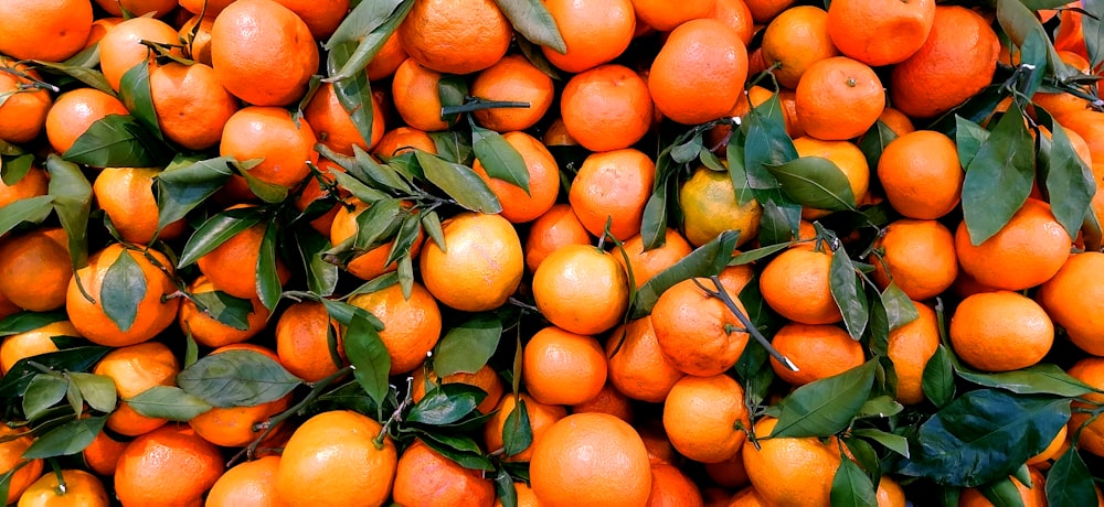 a large pile of oranges with leaves on them
