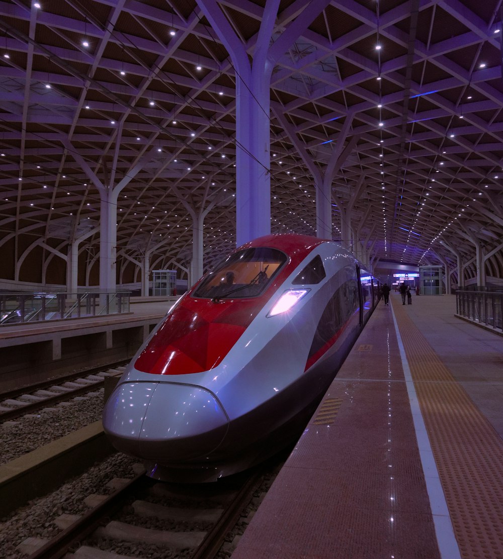 a red and white bullet train pulling into a train station