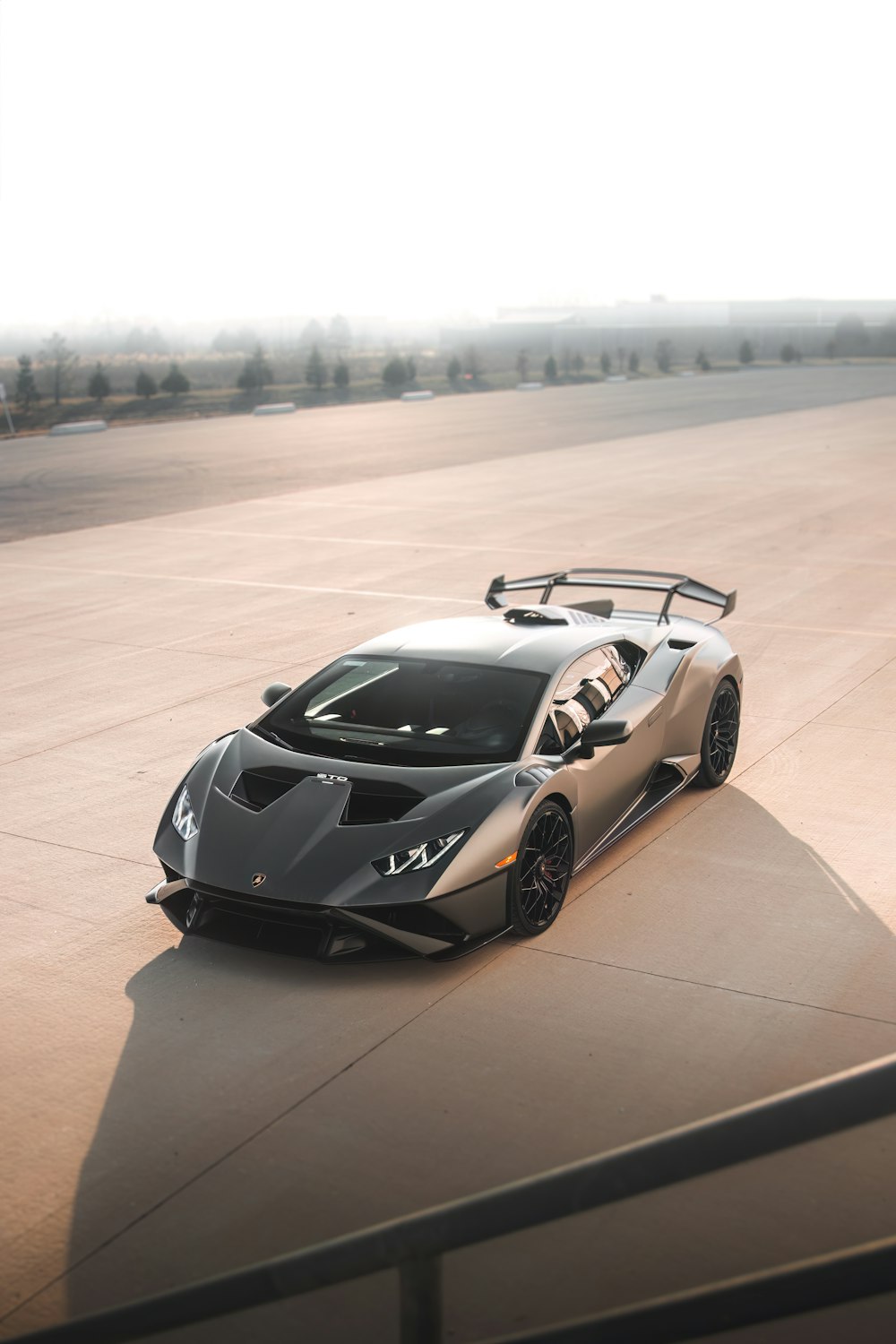 a grey sports car driving down a runway