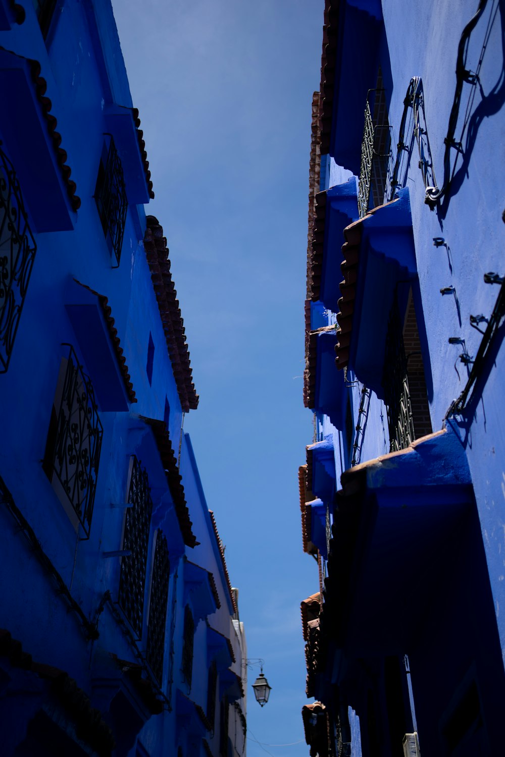 a narrow alley way with blue buildings and a street light