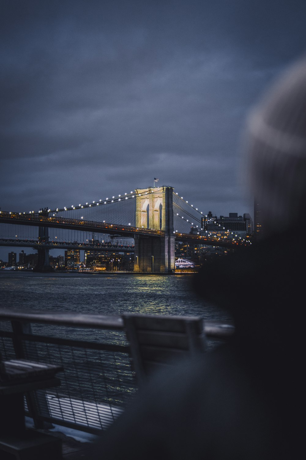 a person sitting on a bench looking at a bridge