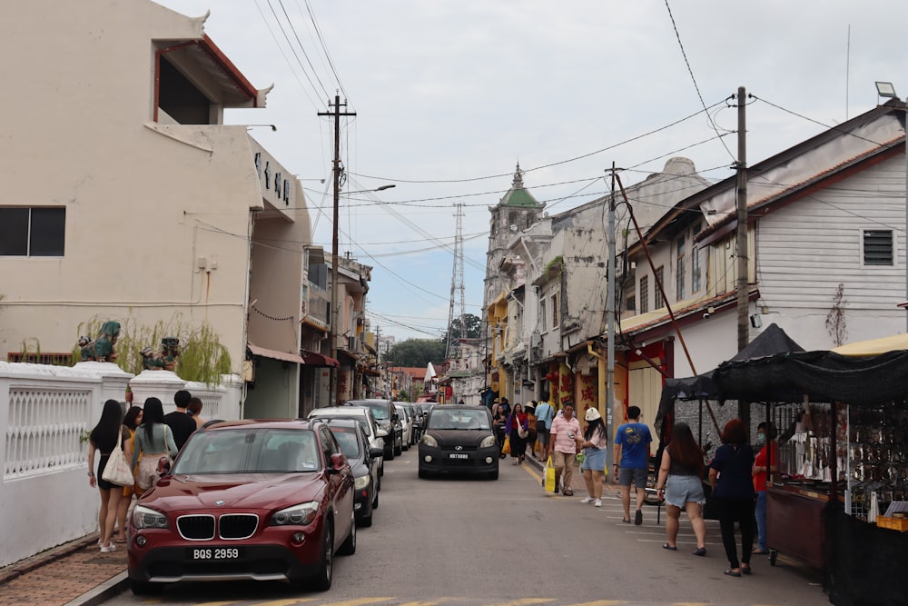 a group of people walking down a street next to parked cars