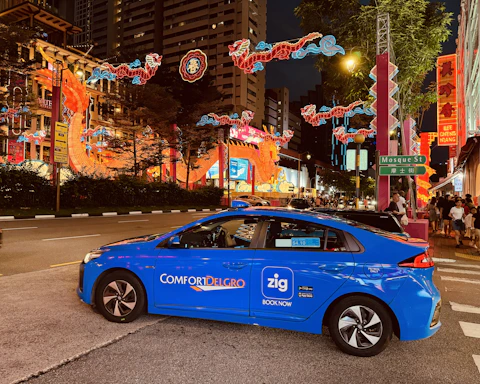 a blue car driving down a street next to tall buildings